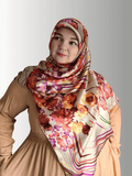 A woman wears a 48x48" silk-blend square hijab with a rich floral design in warm autumn hues.