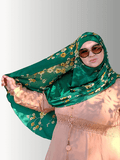 A vibrant emerald green hijab adorned with delicate yellow and white floral patterns, elegantly draped to highlight its soft, flowy fabric. The hijab offers a refreshing, nature-inspired design perfect for brightening up any outfit.