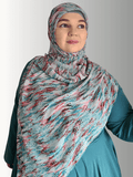 woman wears a chiffon hijab with an abstract pattern in shades of red, blue, and gray, styled with a soft drape.