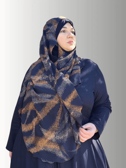 A woman wearing the Luxe Noir Essence Veil, featuring a black chiffon overlay with deep, rich brown patterns. The hijab has a soft jersey base for full coverage and a comfortable, non-slip fit. The intricate design and earthy tones create a sophisticated and elegant look.

