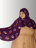 "A rich purple hijab featuring a chiffon overlay with multicolored floral patterns, styled with a beige outfit. Includes front and back views to highlight the flowy design and full coverage."
