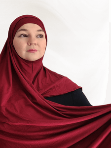 Burgundy-red instant jersey hijab shawl named Pomegranate Wine, featuring a matching undercap and elegant drape on neutral background.
