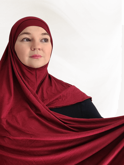 Burgundy-red instant jersey hijab shawl named Pomegranate Wine, featuring a matching undercap and elegant drape on neutral background.
