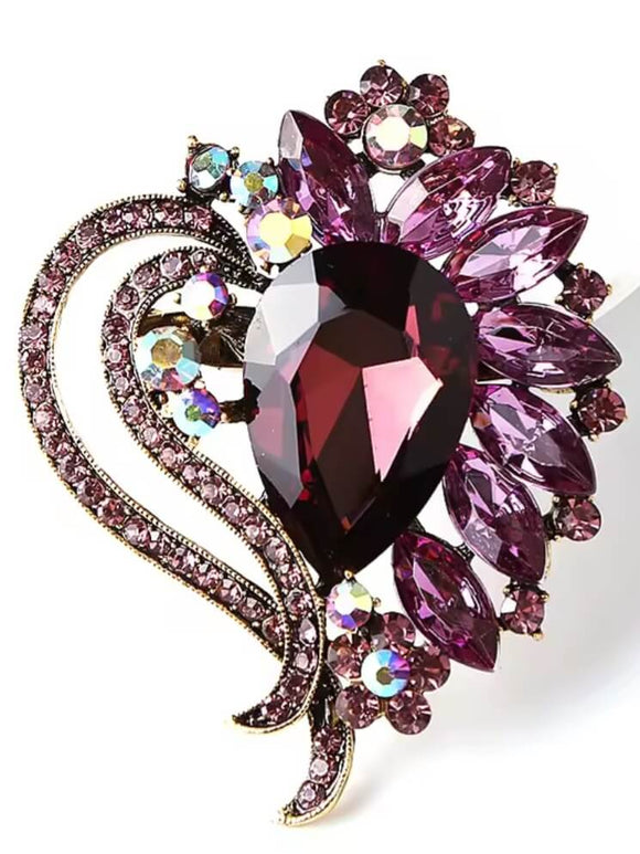 Elegant gold and amethyst brooch with a deep purple teardrop gemstone, floral rhinestone details, and sparkling accents.