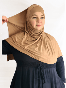 Golden beige instant jersey hijab shawl with a soft, glowing finish and matching undercap displayed in warm natural lighting.
