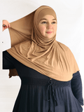 Golden beige instant jersey hijab shawl with a soft, glowing finish and matching undercap displayed in warm natural lighting.
