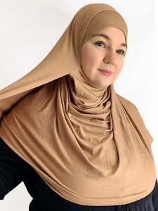 A creamy golden beige jersey double loop hijab with attached undercap, displayed with soft, flattering lighting to show its smooth drape and neutral tone.