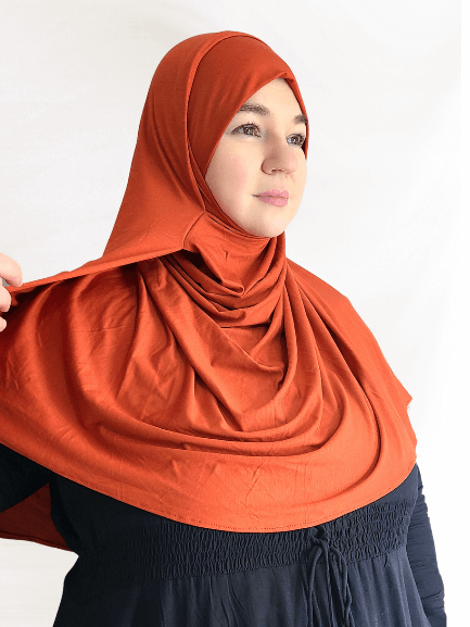 Burnt orange double loop jersey hijab with attached undercap, styled in smooth, warm-toned folds for an effortless and bold everyday look.
