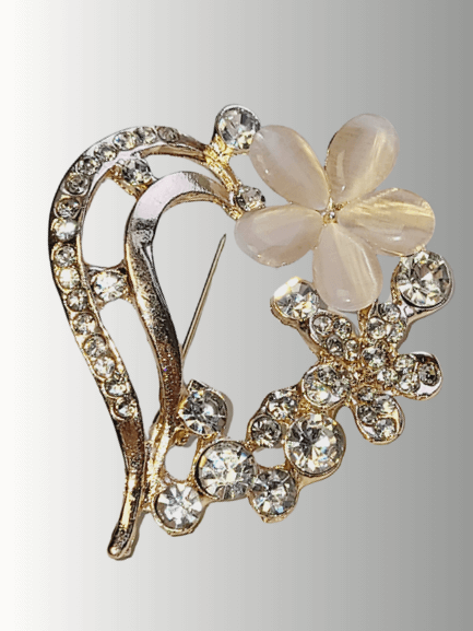 Gold heart-shaped brooch with clear rhinestones and a mother-of-pearl flower.