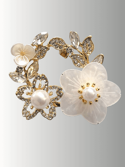 Gold floral hijab brooch with a pearl centerpiece, translucent flower petals, and crystal-encrusted leaves.
